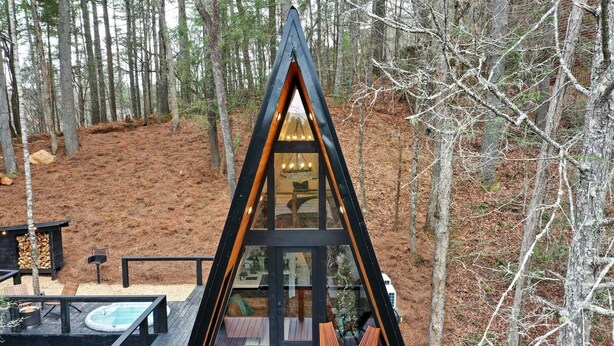 Un chalet moderne en forme de « A », doté d’une façade en verre, d’un espace salon extérieur et d’une terrasse.