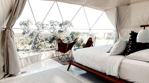 A tented room with a bed, a chair, and a view of the outdoors. - Breathtaking Dome with Spectacular Outdoor Living and Chic Elegant Interior in Texas (Fischer)