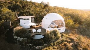 Una tienda de campaña con forma de cúpula, un área de estar circular y una pequeña piscina.