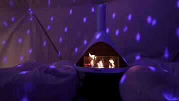 A tent with a fire inside, surrounded by blankets.
