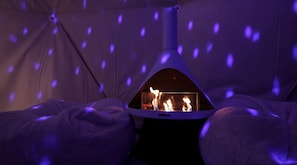 A tent with a fire inside, surrounded by blankets. - Breathtaking Dome with Spectacular Outdoor Living and Chic Elegant Interior in Texas (Fischer)