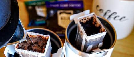 A coffee maker with a cup of coffee, a coffee mug, and a box of coffee pods on a wooden surface.