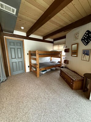 Une chambre avec un lit superposé, un bureau, une chaise, un miroir et une porte.