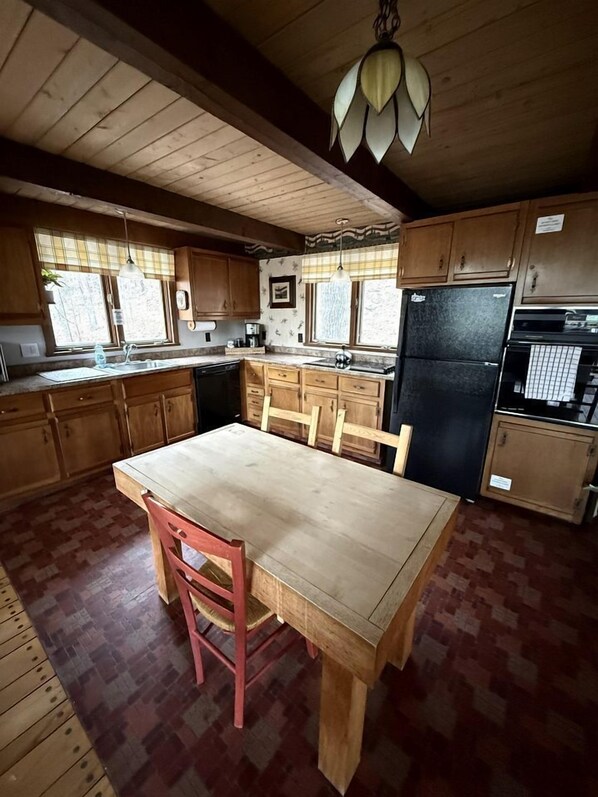 A kitchen with wooden cabinets, a black refrigerator, and a dining table with chairs.