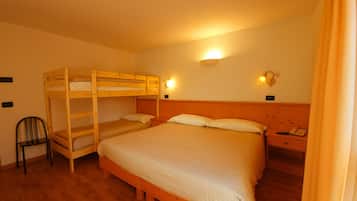 Ein Zimmer mit Etagenbett, Einzelbett, Stuhl, Nachttischen und Wandlampen.