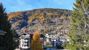 A residential area with multi-story buildings, a mountain in the background, and autumn-colored trees. - Hotel Bleis (Ponte di Legno)