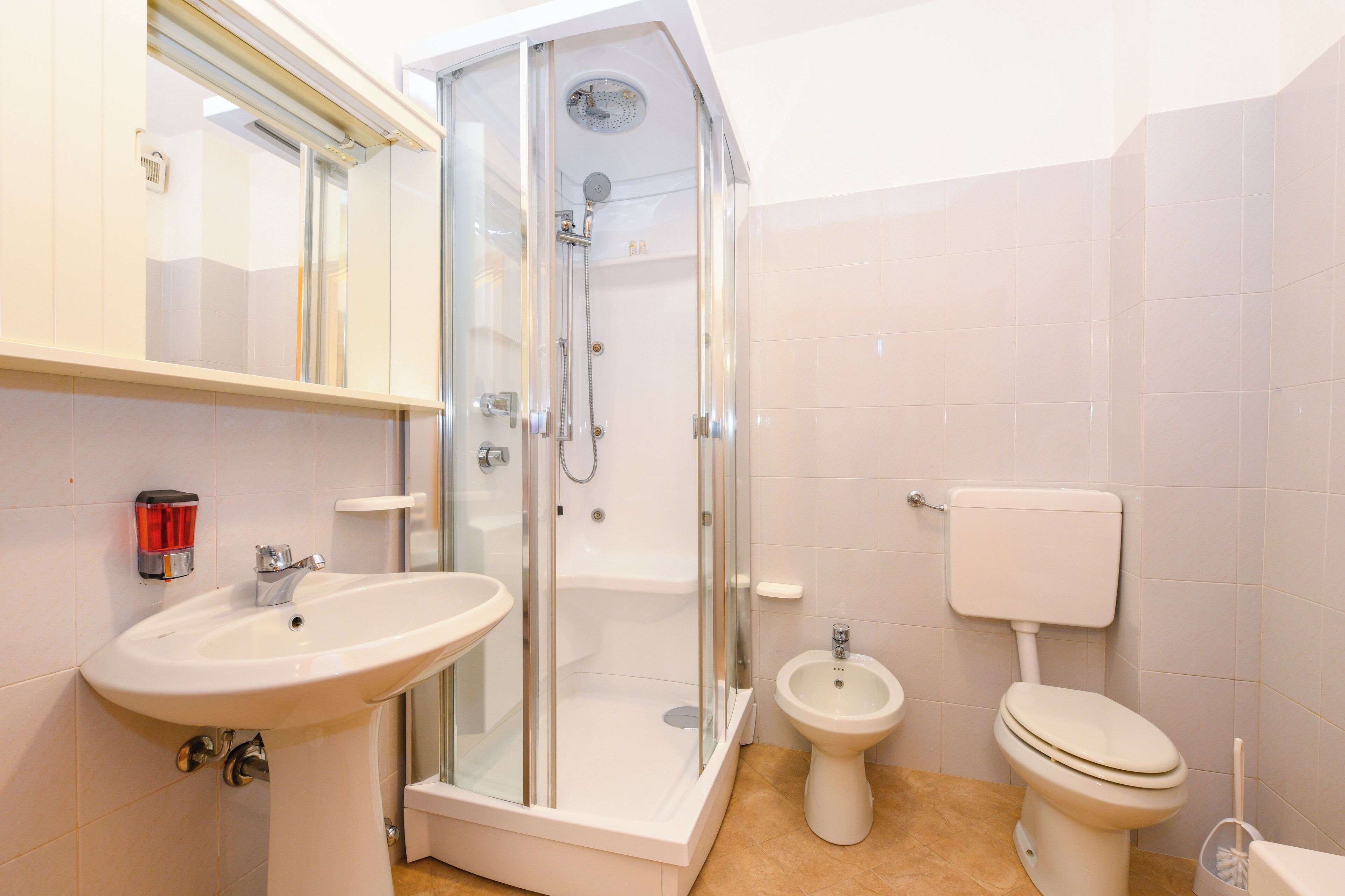 Ein Badezimmer mit Duschkabine, Standwaschbecken, Bidet und Toilette.