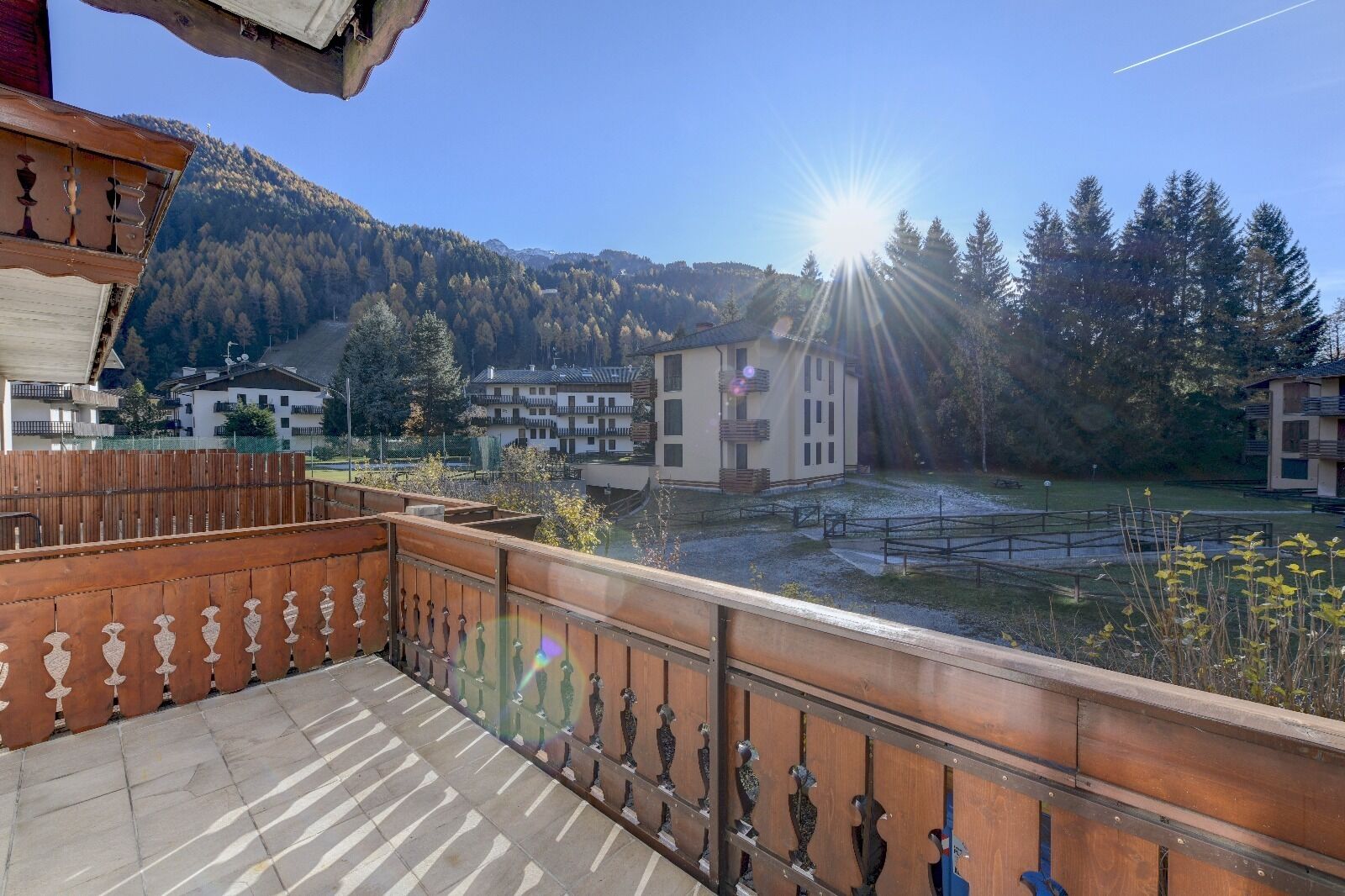 A balcony with a view of a mountain, a lake, and buildings in the background.