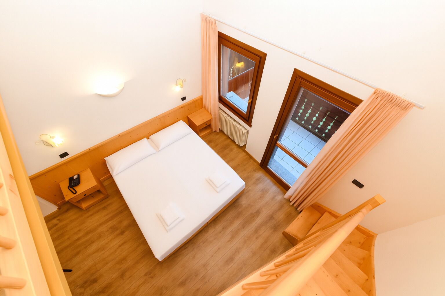 Una camera da letto con un letto, un comodino e una finestra con tende.