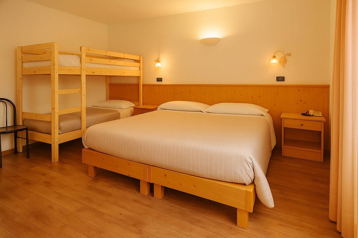 A room with a bunk bed, a single bed, a chair, a nightstand, and a wall-mounted light fixture.