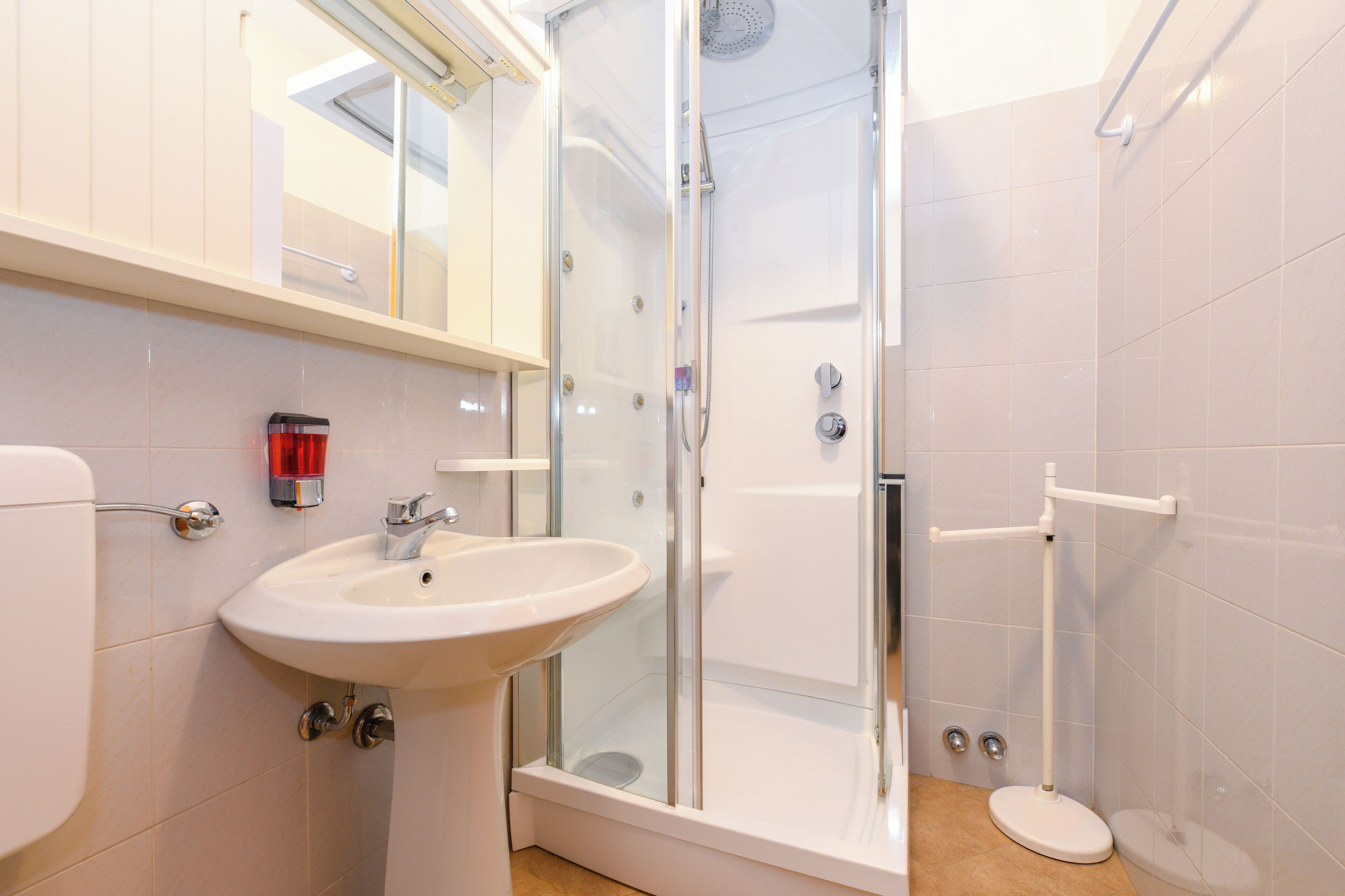 Un baño moderno con ducha de vidrio, lavamanos blanco y retrete.
