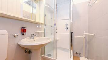 Un baño moderno con ducha de vidrio, lavamanos blanco y retrete.