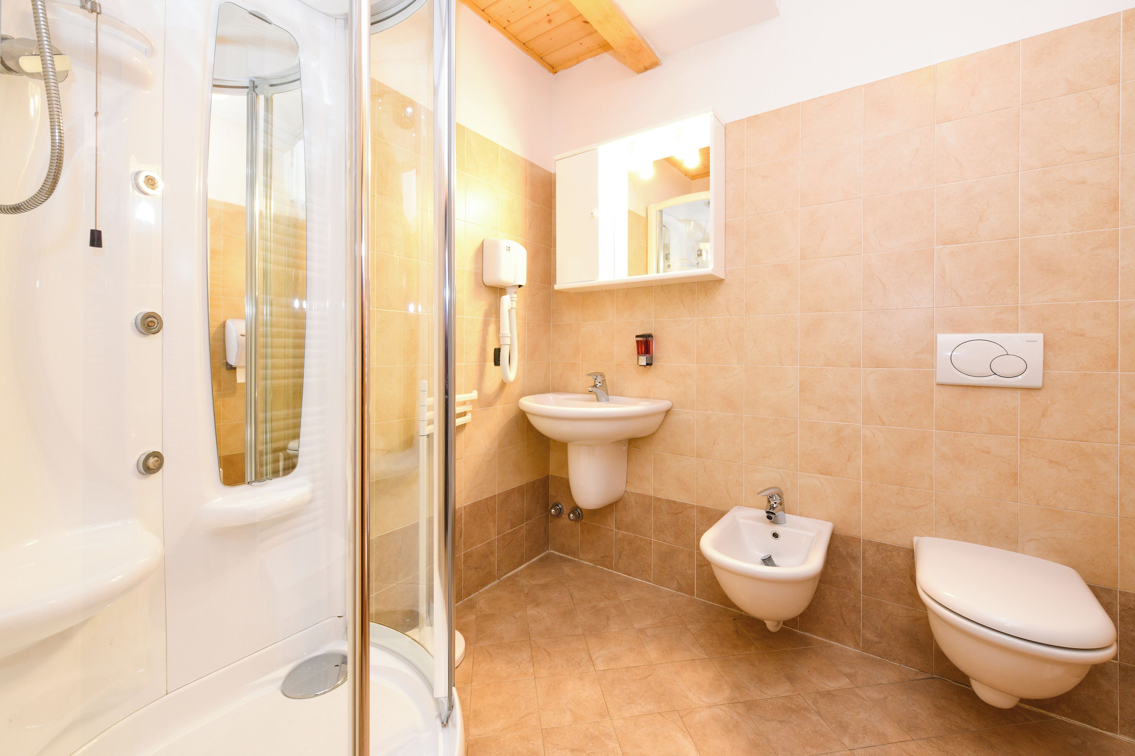 Une salle de bain moderne avec une douche à parois de verre, un lavabo sur colonne, un bidet et des toilettes.