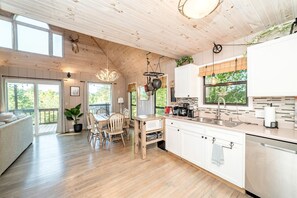 Une cuisine spacieuse avec des meubles de rangement en bois, un coin repas avec une table et des chaises, et une grande fenêtre donnant sur un paysage verdoyant.