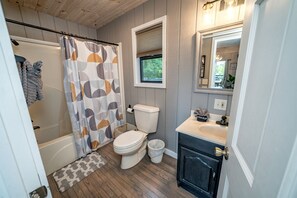 Une salle de bain équipée d’un rideau de douche, de toilettes, d’un lavabo et d’un miroir.