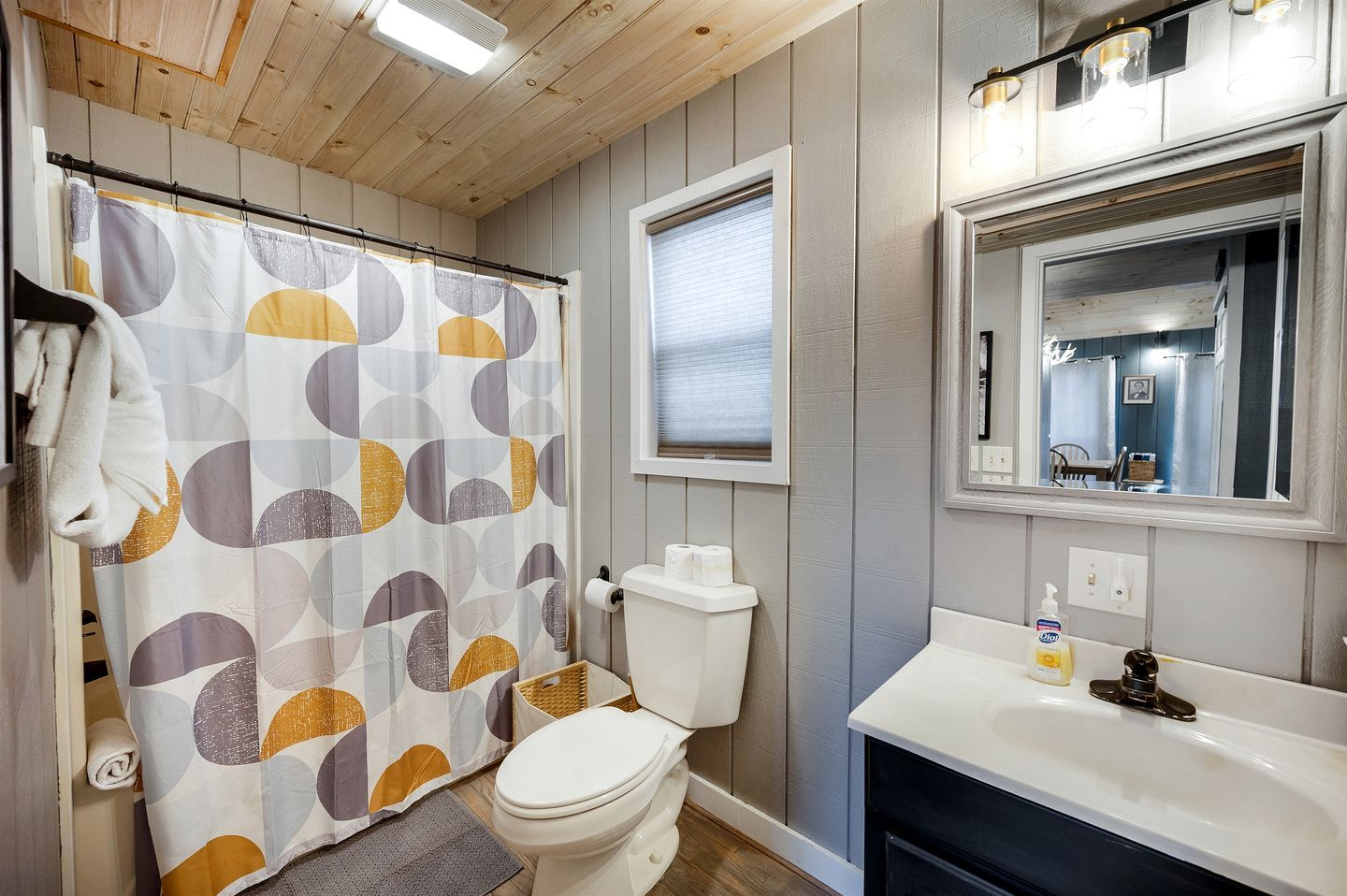 A bathroom with a toilet, sink, shower curtain, and a mirror.