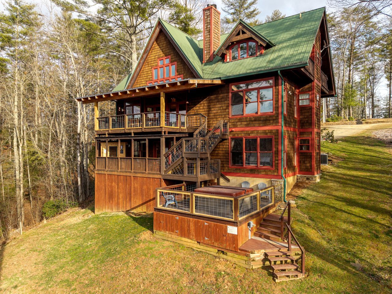 A wooden cabin with a balcony, a covered porch, and a chimney.