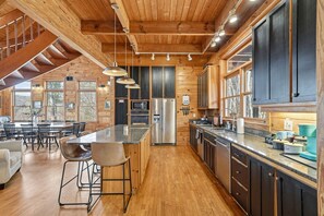 A spacious kitchen with wooden cabinetry, a central island, and a dining area with bar stools.