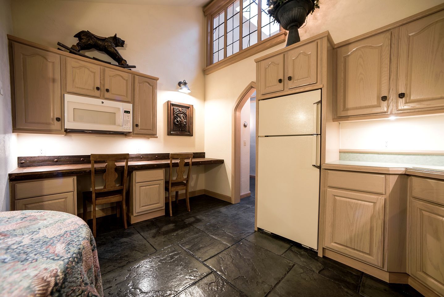 Une cuisine dotée de meubles en bois, d’un four à micro-ondes, d’un réfrigérateur et d’un coin repas avec des chaises et une table.
