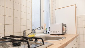 A kitchen with a gas stove, a microwave, and a sink. - Basic 2BR Apt Near Westbahnhof (Vienna)
