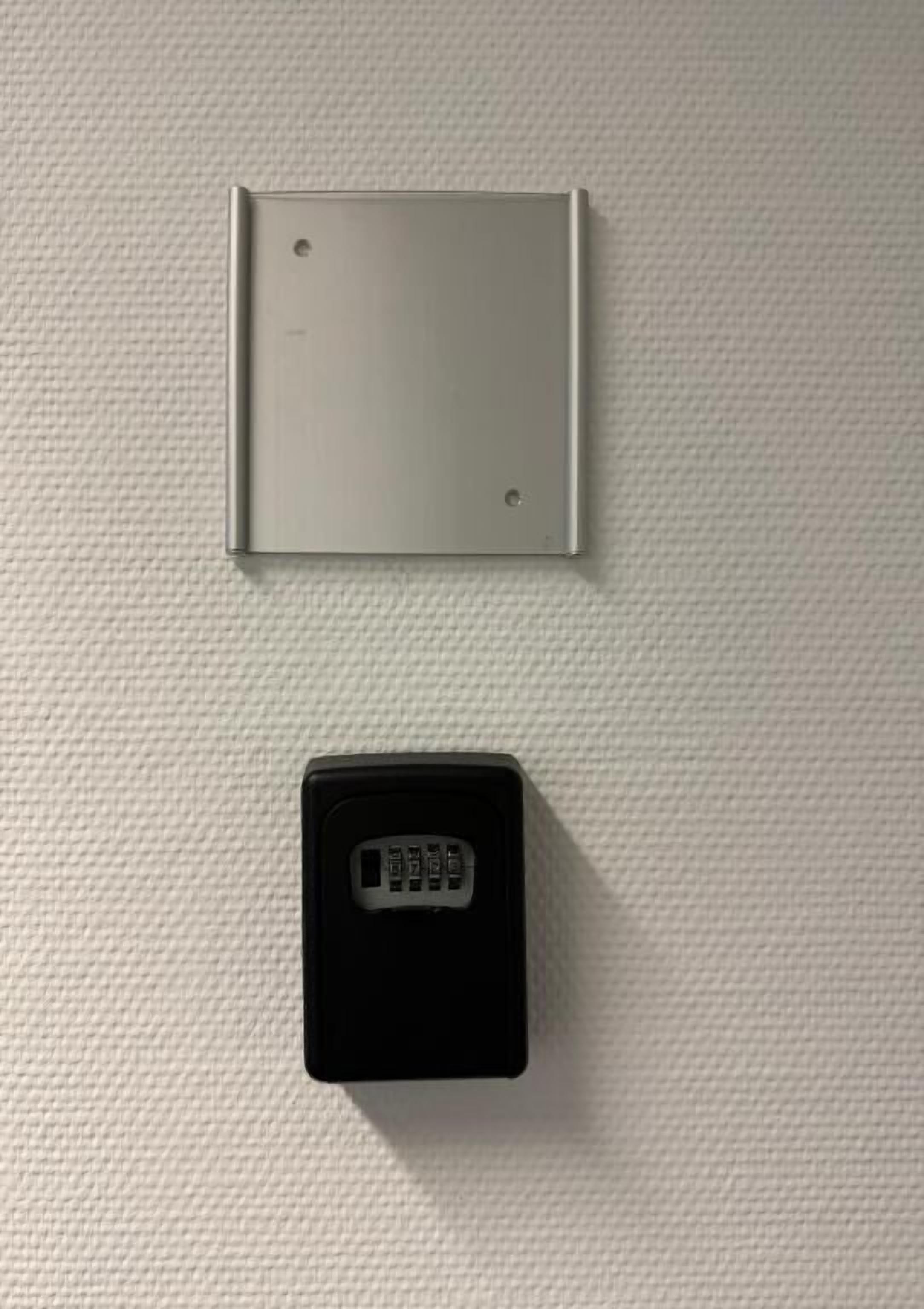 A wall-mounted control panel with a keypad and a metal plate above it.