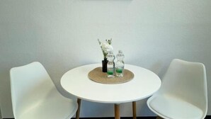 A room with a round white table, two white chairs, a framed picture on the wall, and a small plant on the table. - StayFlex Nürnberg (Nuremberg)