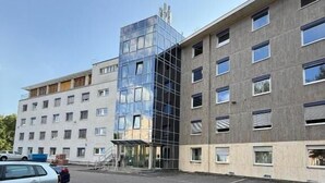 A modern building with a glass facade and a parking lot. - StayFlex Nürnberg (Nuremberg)