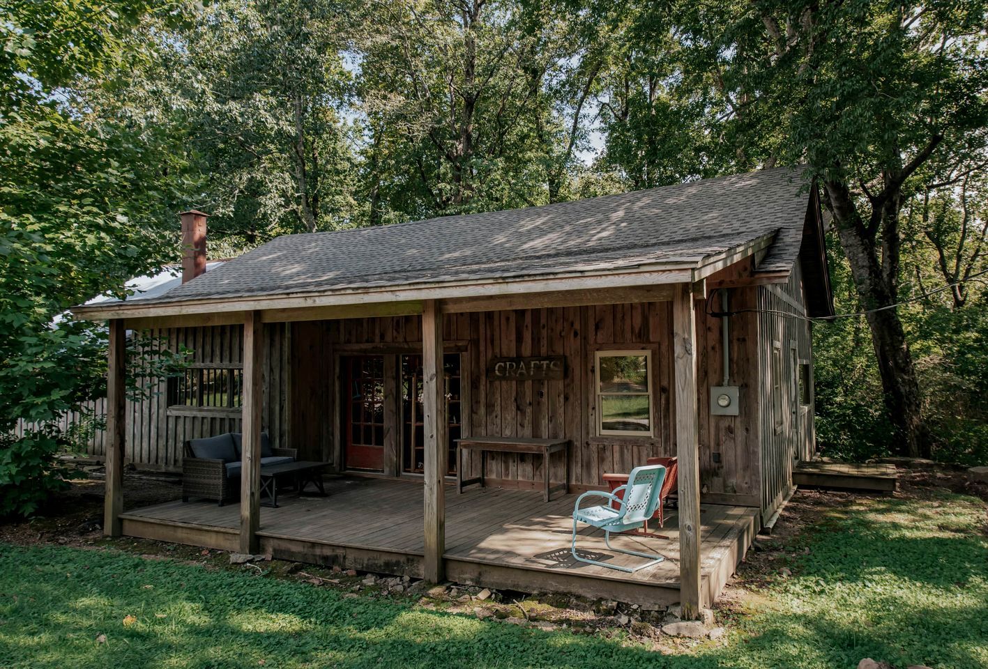 A rustic wooden cabin with a porch, a sign reading 'CRAFTS,' and a small table and chair.