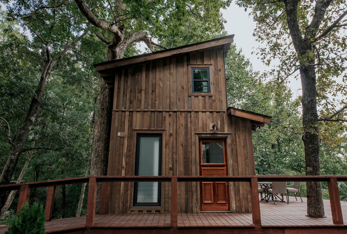 A wooden cabin with a deck, a large window, and a door.