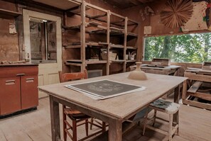 Eine rustikale Werkstatt mit Holzmöbeln, einem Zeichenbrett und Regalen voller Werkzeuge und Materialien.