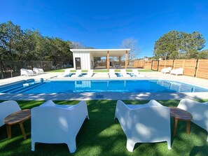 A swimming pool with lounge chairs and a covered seating area.