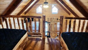 An attic bedroom with wooden beams, a sloped ceiling, and two beds. - Gorgeous Cabin Great for Family Getaways by Tappan Lake in Ohio (Deersville)