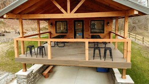 A wooden cabin with a porch, two windows, and a door. - Gorgeous Cabin Great for Family Getaways by Tappan Lake in Ohio (Deersville)