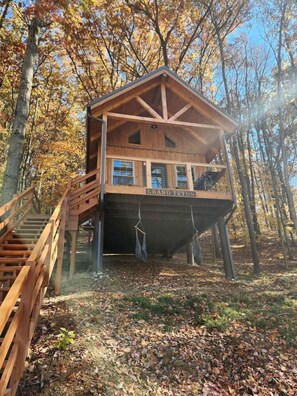 Une cabane en bois dotée d’un balcon, portant l’inscription « GRAND TETON », et entourée d’arbres.