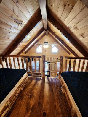 An attic bedroom with wooden beams, a sloped ceiling, and two beds.