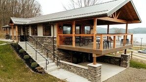 A lodge with a stone facade, wooden deck, and outdoor seating area. - Gorgeous Cabin Great for Family Getaways by Tappan Lake in Ohio (Deersville)