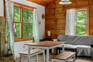A cozy cabin interior with a wooden interior, a sofa, a table, and two benches.