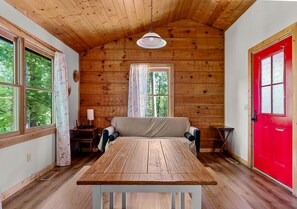 Una cabaña con interior de madera, una mesa de comedor, un sofá y una puerta roja.