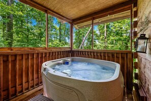 A hot tub in a wooden deck with a view of a forest.