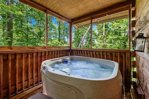 A hot tub in a wooden deck with a view of a forest. - Charming Cabin with Spa and Mountain Views in Sevierville, Tennessee (Sevierville)