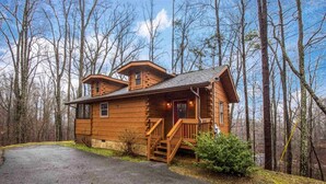 A wooden cabin with a porch, a staircase, and a driveway. - Charming Cabin with Spa and Mountain Views in Sevierville, Tennessee (Sevierville)