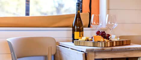 A dining table with a bottle of wine, cheese, and grapes.