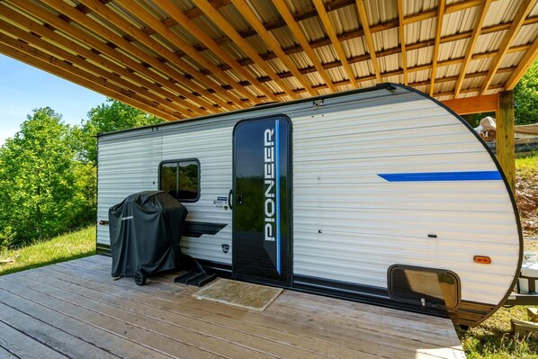 A Pioneer RV parked on a wooden deck with a covered grill area.