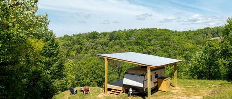 A campsite with a covered RV area, a picnic table, and a chair.