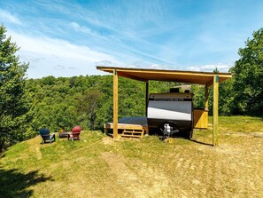A camping area with a covered RV, two chairs, and a picnic table.