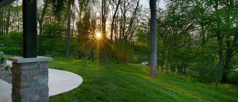 A well-maintained lawn with a stone pillar and a curved pathway leading to a covered area.
