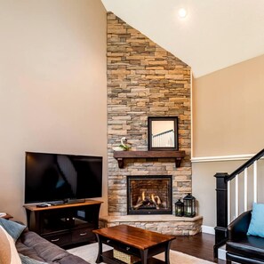A living room with a stone fireplace, a flat-screen TV, a sofa, and a coffee table.