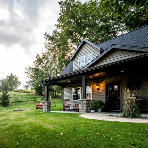 A two-story house with a covered porch, stone pillars, and a well-maintained lawn.