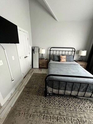 A bedroom with a bed, bedside tables, a wardrobe, and a patterned rug.
