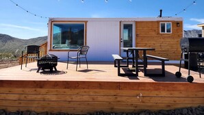 A wooden deck with a barbecue grill, a table, and chairs.